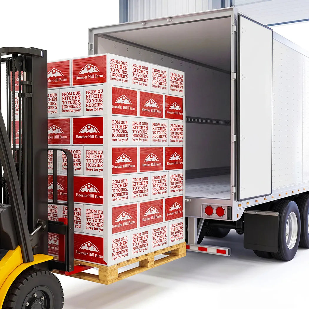 Pallet of Hooray Hill Farm boxes being loaded onto a truck with a forklift.