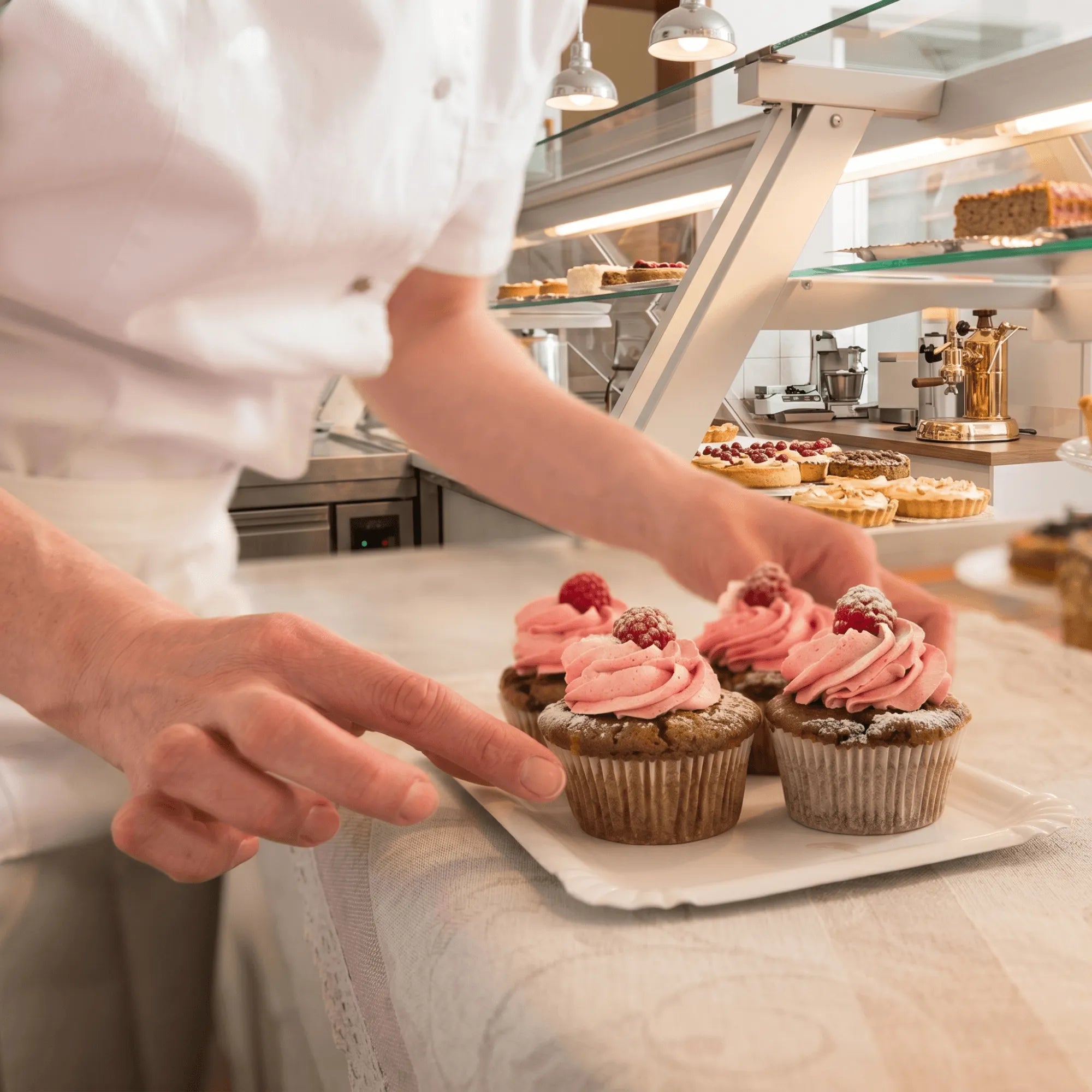 Person in a kitchen setting with cupcakes on a tray