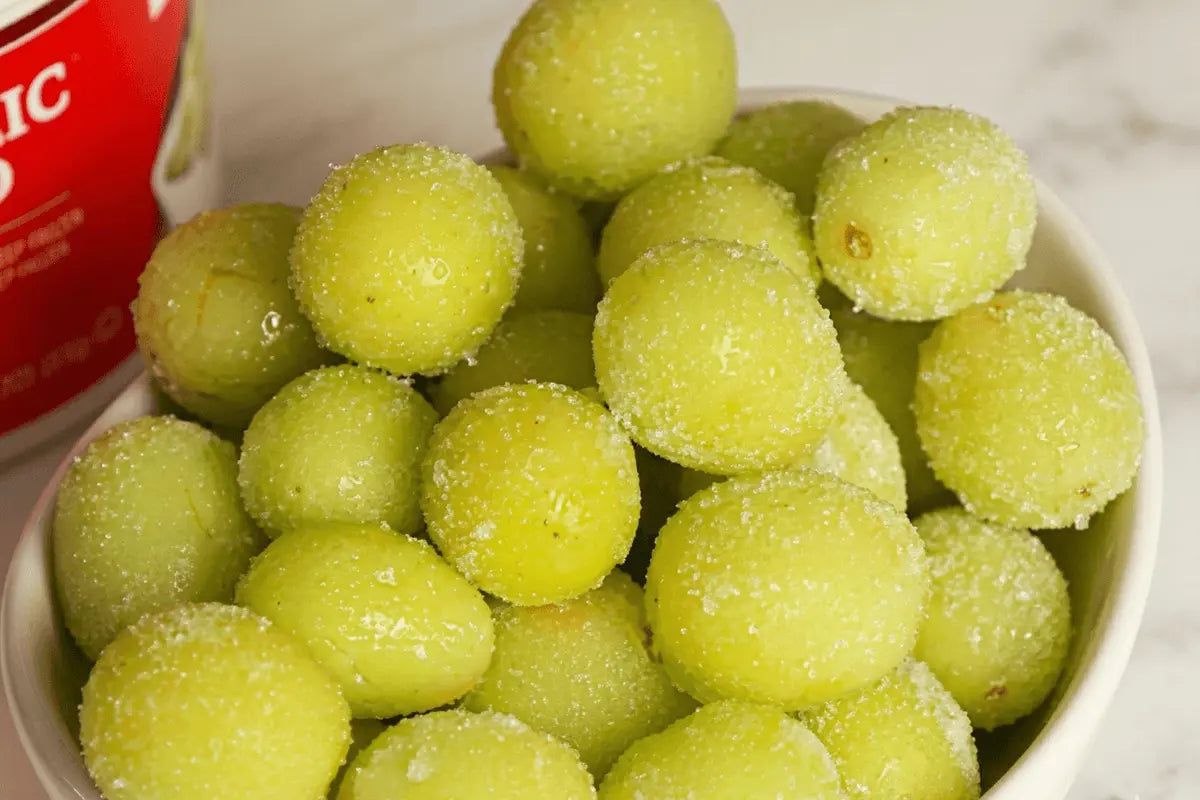 Frozen sour grapes coated in sugar and citric acid on a parchment-lined tray