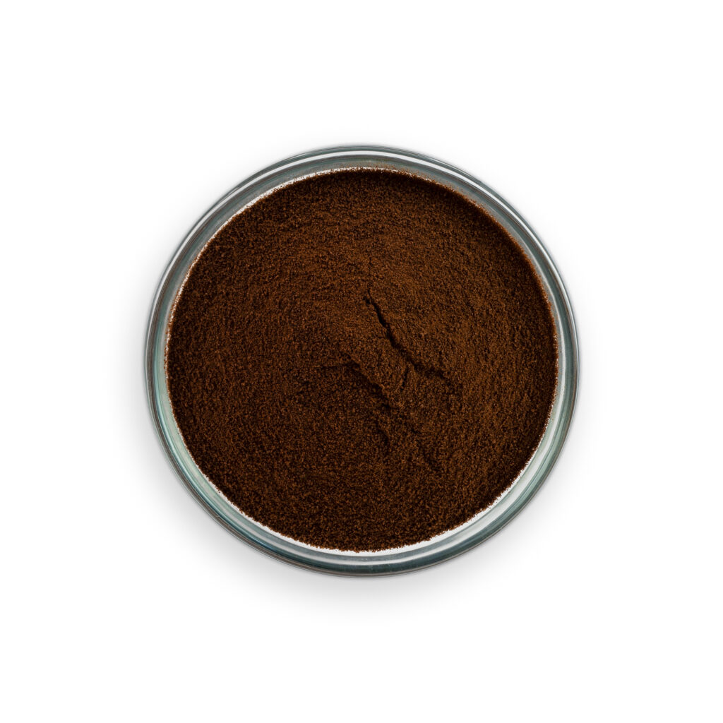 Close-up of a container of dark brown powder on a white background
